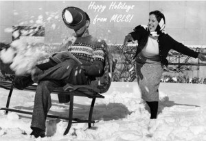 Woman throwing snowball at man sitting on bench reading a book